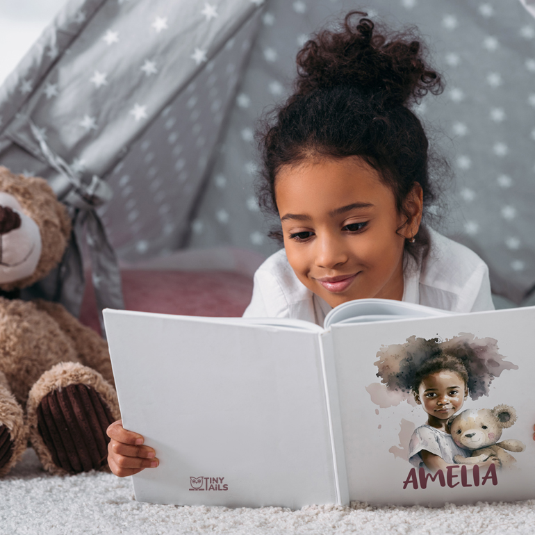 Girl with curly hair reading her personalized storybook featuring her character with a teddy bear